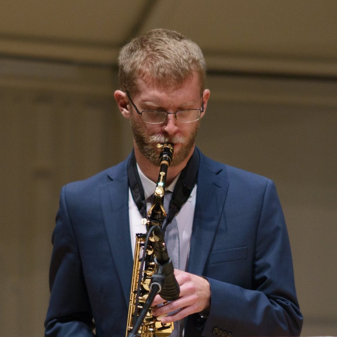 Mitch Borchardt playing alto saxophone in concert, wearing a navy suit